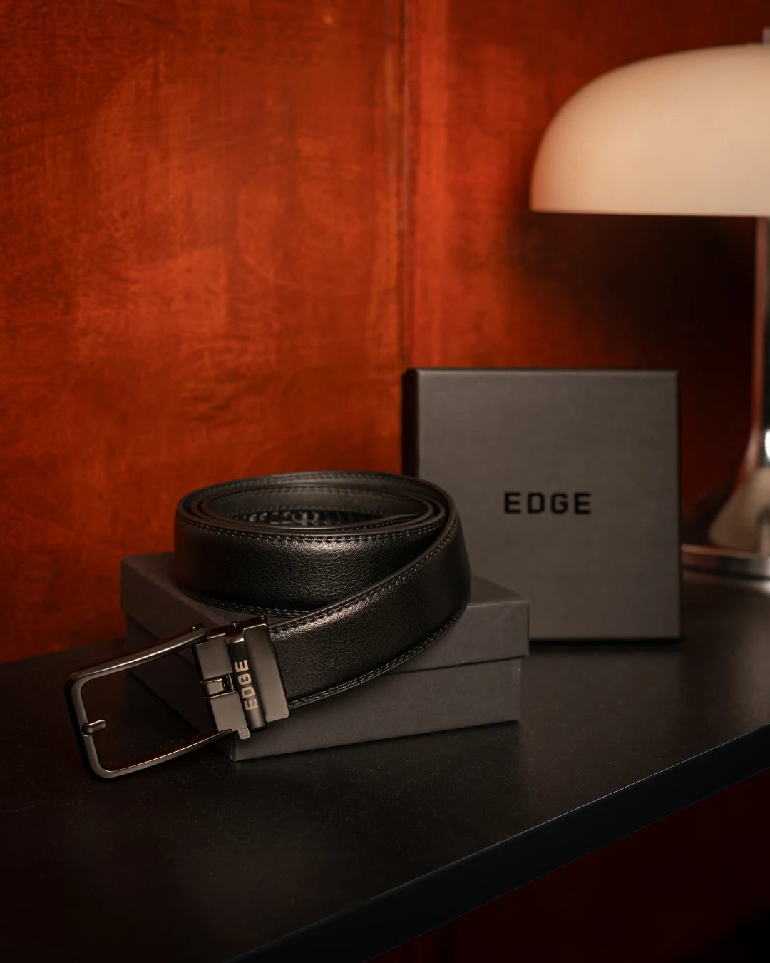 Crni EDGE kaiš na stolu pored crne poklon kutije EDGE