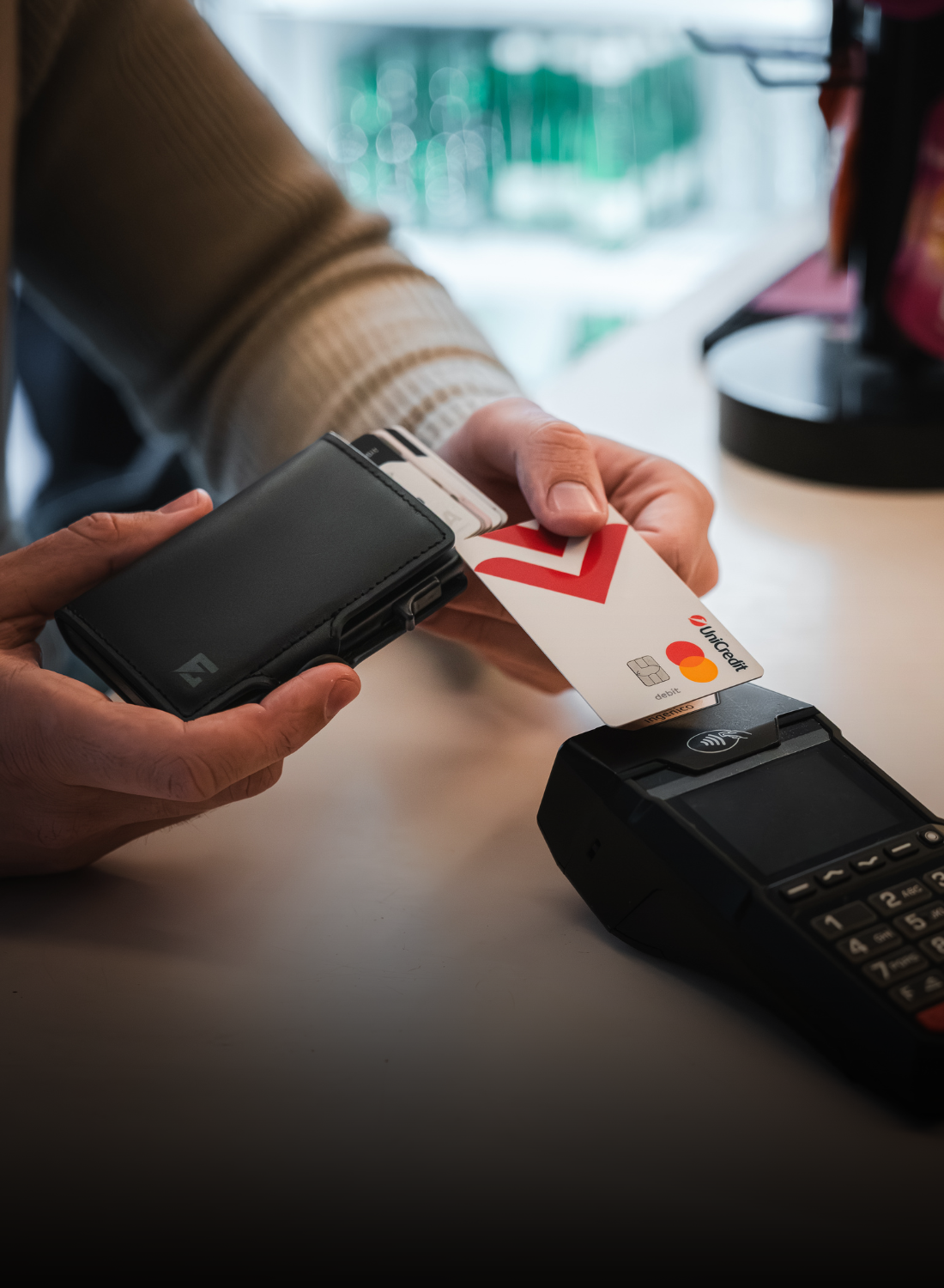 Beskontaktno plaćanje karticom iz crnog EDGE Click novčanika na POS terminalu